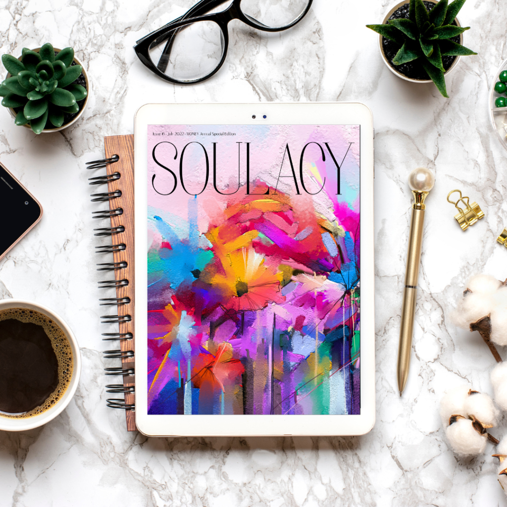 Colorfully painted magazine cover of Soulacy Magazine displayed on an iPad on a marble backdrop surrounded by a pen, cup of coffee, and succulent plant 